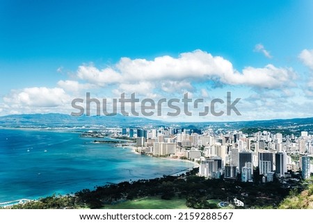 A sweeping view of Honolulu, Hawaii, USA, on the coast of the Pacific ocean under a bright cloudy sky