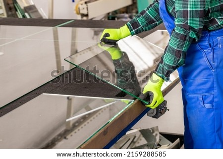 The glazier removes the cut glass from the specialized table in the glass factory, Cutting glass panels  Royalty-Free Stock Photo #2159288585