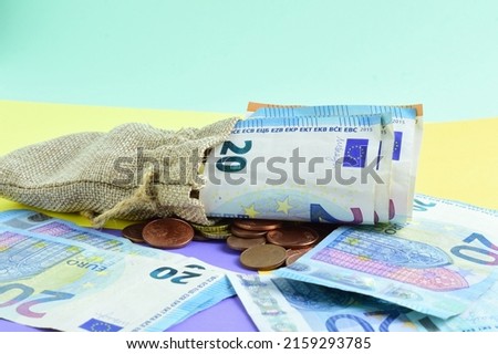 Scattered twenty euro bills, and small sack with coins.
