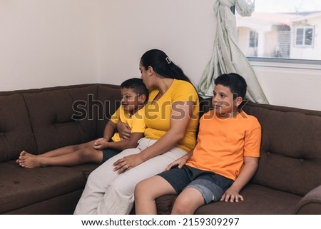 mom giving a hug and a kiss to her son, sitting in the armchair