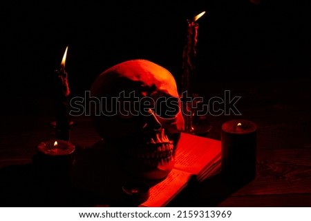 Humans skull and orange light from burning candles in the dark. Death and horror. Satanic ritual concept.