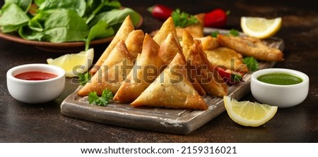 Fried samosas with vegetable filling, popular Indian snacks on wooden board Royalty-Free Stock Photo #2159316021