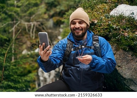 Positive delighted sportsman taking picture in the forest