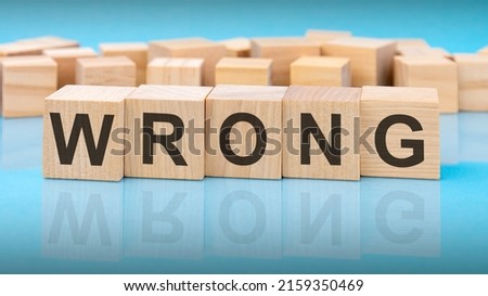 wooden blocks with the letters Wrong on the bright surface of a blue table. the inscription on the cubes is reflected from the surface.