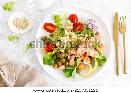 Grilled salmon salad with fresh lettuce, tomatoes, green olives, red onion and pasta. Healthy food, diet. Top view