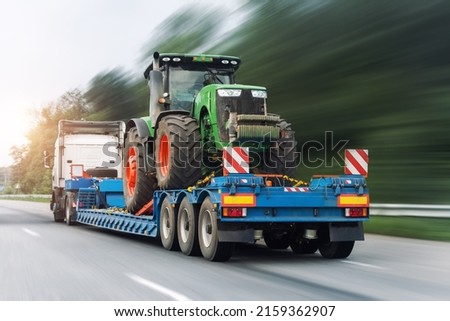 POV heavy industrial truck semi trailer flatbed platform transport one big modern farming tractor machine on common highway road at bright day sky. Agricultural equipment transportation service work Royalty-Free Stock Photo #2159362907