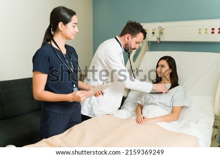 Happy patient feeling better after a medical surgery at the hospital. Doctor and nurse with a woman checking vital signs