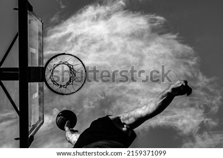 A grayscale shot of an airborne athlete about to shoot a basketball Royalty-Free Stock Photo #2159371099