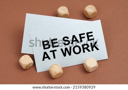 The concept of industrial safety. On a brown surface, wooden cubes and a business card with the inscription - Be safe at work