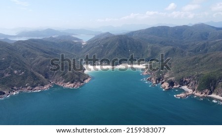 An aerial view of rocky mountains and blue sea under the clear sky