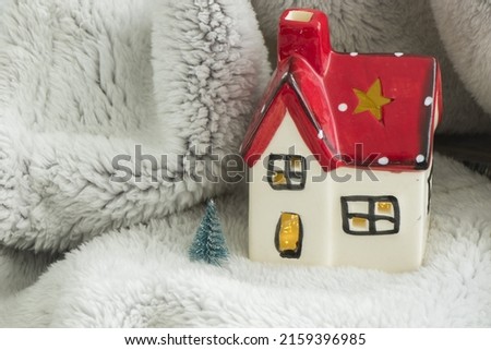 A toy house with a red roof, pine tree, and snow - New year's concept