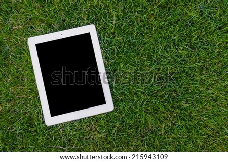 Empty tablet on grass background
