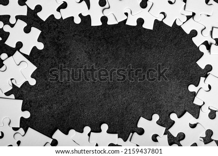 Frame made of jigsaw puzzle pieces on black background. Framing in the form of a rectangle, made of a white jigsaw puzzle. Frame text and jigsaw puzzles.