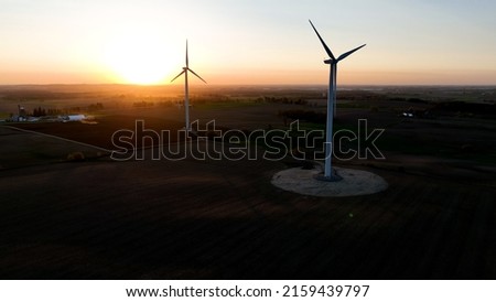 Two wind turbines are pictured at sunset, as the rural landscape is captured as the dusk sun shines bright.