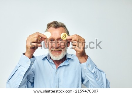 Portrait of happy senior man finance gold coins bitcoin near face isolated background