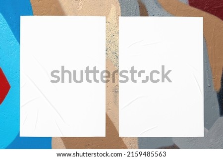 Closeup of colorful blue red beige painted urban wall texture with two wrinkled glued poster templates. Modern mockup for design presentation. Creative urban city background. 