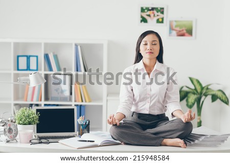 Female office worker meditating on her work place Royalty-Free Stock Photo #215948584