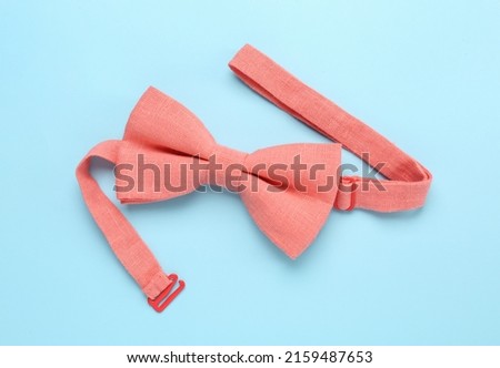 Stylish pink bow tie on light blue background, top view