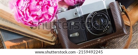 retro photo camera with books and fresh pink peony flowers