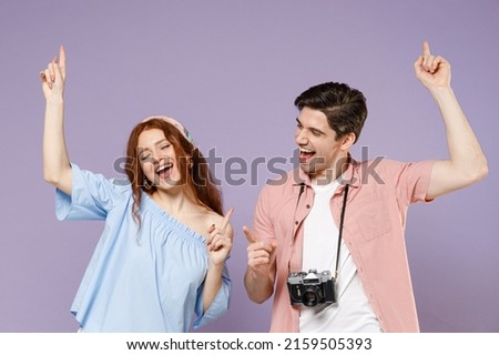 Two happy traveler tourist woman man couple in summer clothes do winner gesture point finger up isolated on purple background Passenger travel abroad on weekends getaway Air flight journey concept. Royalty-Free Stock Photo #2159505393