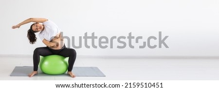 Banner with fexible pregnant woman doing gymnastics on rug on the floor on white background with copy space. Preparing the body for easy childbirth concept