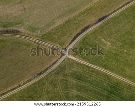 Aerial view of a dirt road crossing in the fields in spring