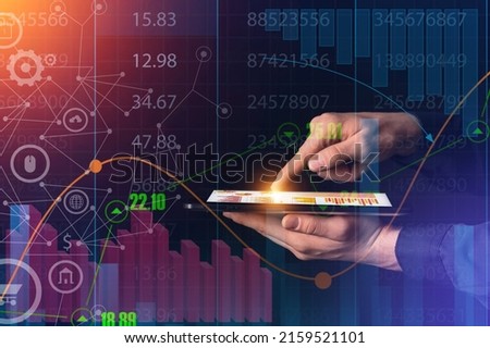 Hands of economist with tablet computer using virtual screen with diagrams on dark background Royalty-Free Stock Photo #2159521101