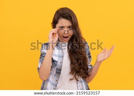 shocked teen kid in checkered shirt and glasses on yellow background