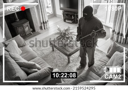 CCTV surveillance security camera of burglar breaking into home via back door window with crowbar house robbery concept Royalty-Free Stock Photo #2159524295