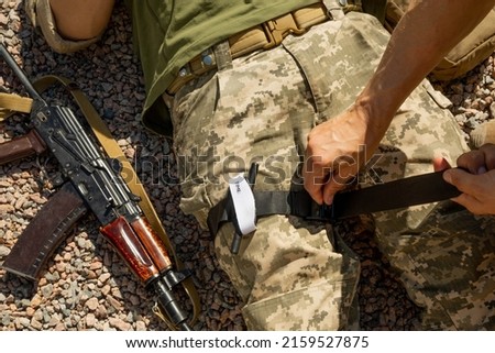 Army medics practice applying a tourniquet to the leg of a wounded soldier. Combat tactical equipment. Combat use Turnstile. The concept of military medicine. Royalty-Free Stock Photo #2159527875