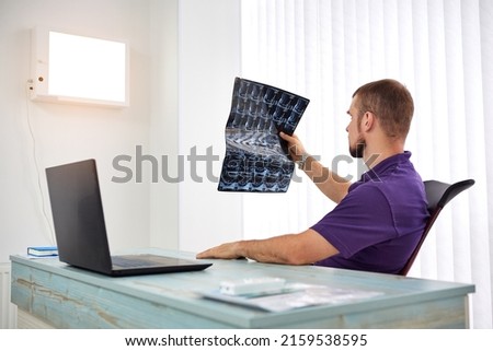 The physiotherapist doctor examining X-ray or mri picture in privat clinic. Surgeon or orthopedic in rehabilitation center. Medicine and healthcare concept