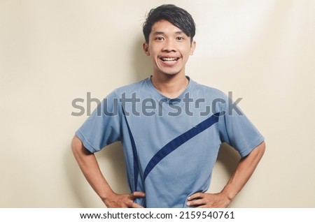Asian young man in sports t-shirt looking happy isolated on background