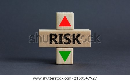 Risk level symbol. A wooden cube with up icon. Wooden block with the concept word Risk. Beautiful grey table grey background. Copy space. Business and Risk level concept.