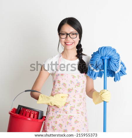 Portrait of Asian Chinese woman housekeeping, holding bucket and mop on plain background.