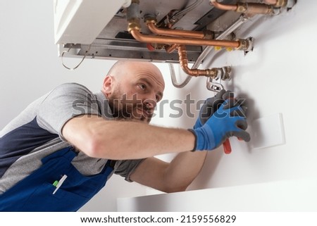 Professional engineer installing a natural gas boiler at home, he is checking the pipes Royalty-Free Stock Photo #2159556829
