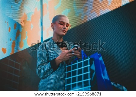 Image of a beautiful young woman posing against a led panel. Shaved head teenager with alternative look making urban portraits