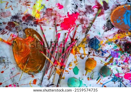 Top view of colorful color mixing on canvas background with paintbrush, paint palette and paint bottle. Kids art background

