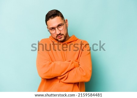 Young hispanic man isolated on blue background who is bored, fatigued and need a relax day.