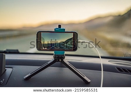 The phone on a tripod in the car takes a video of the scenic road