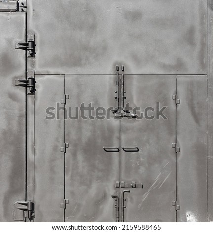 Black painted garage gates with door under the sunlight. Background texture or resource for 3d modelling or texturing