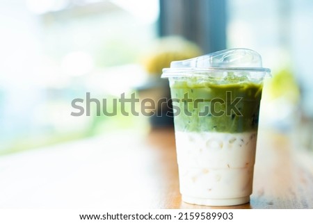 Japanese Matcha green tea ice latte on table.Iced mocha or matcha green tea latte in takeaway cup in cafe restaurant.Drinking Menu picture.Matcha green milk tea on wooden table in cafe.Japanese drink.