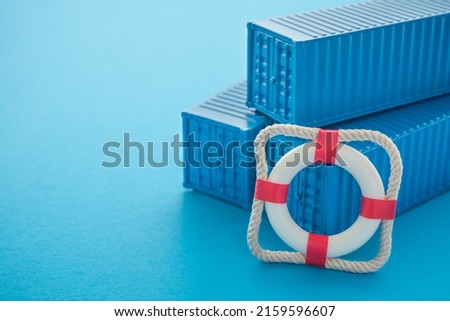 Lifebuoy with blue containers on blue background with copy space. Marine cargo shipment or freight insurance in global shipping and logistic industry. Insurance is risk management control. Royalty-Free Stock Photo #2159596607