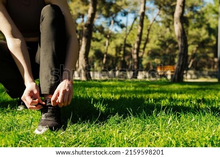 Closeup of female sport fitness runner getting ready for jogging outdoors. Running shoes - woman tying shoe laces. Copy space.