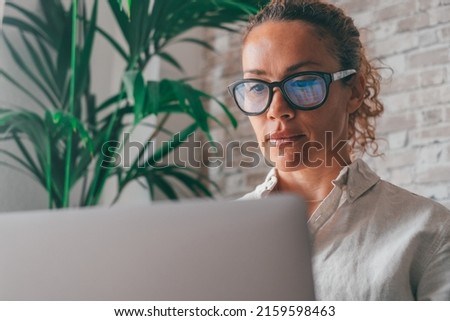 Close up rear view young woman using laptop and calculator, working on project, checking financial documents, sitting at table at home, looking at computer screen with diagrams, calculating bills Royalty-Free Stock Photo #2159598463