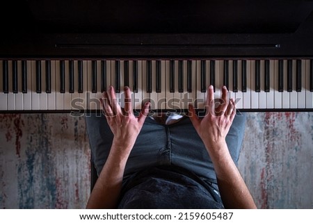 Male hands on the piano keys, top view.