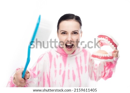 fighting brunette with a huge toothbrush and a tooth jaw in her hands, on a white background. High quality photo