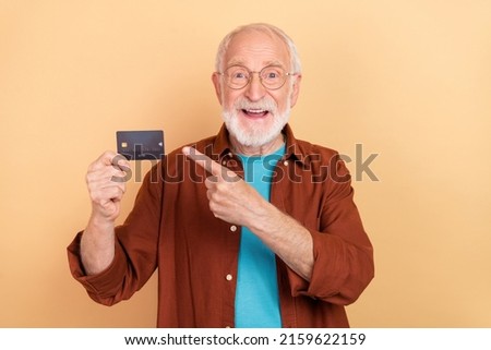 Photo of excited good mood positive grandfather recommend savings salary plastic card isolated on beige color background