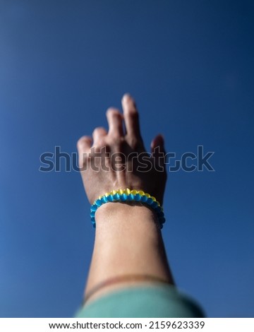 Bracelets mascots in Ukrainian colors. Gentle female hand against the sky. The concept of peace and the absence of war