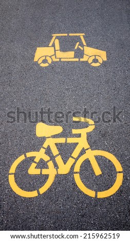yellow painted sign for bikes and car lane