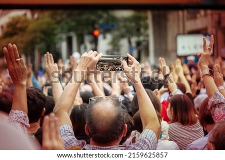 An old man holding a phone to take pictures of pro democracy protesters.